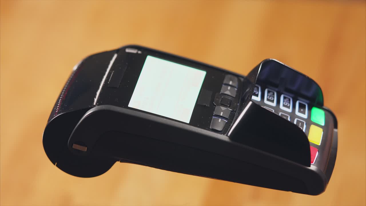 Hand holding credit card over a payment terminal