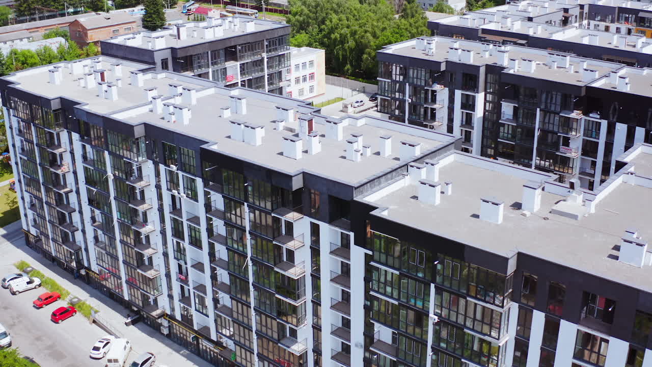 Modern apartment buildings in the city. New residential complex with high-raised buildings of modern design. Roofs of multi-storey buildings on urban background. Aerial view.