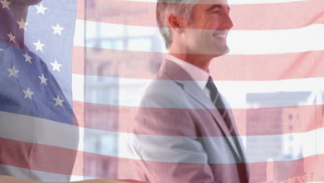 waving american flag against mid section of businessman and businesswoman shaking hands