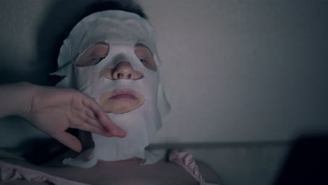 beauty salon visitor in white regenerating sheet mask close