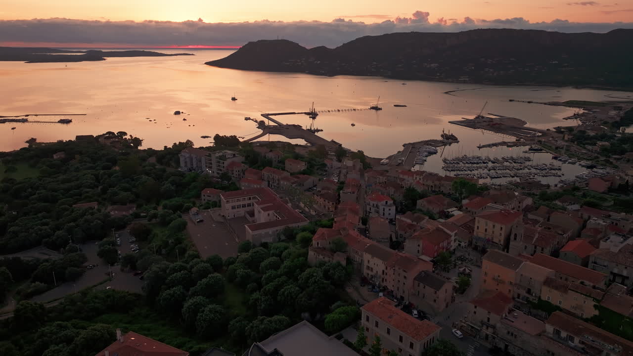 Aerial drone shot of the old town of Porto vecchio, Corsica, France at sunrise. High view of the citadel and the harbor. Warm colorful sky before the sun rises. First lights, golden hour