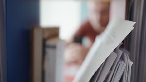 blurred person in the background using a smartphone while important documents are in sharp focus—highlighting distraction and lack of concentration