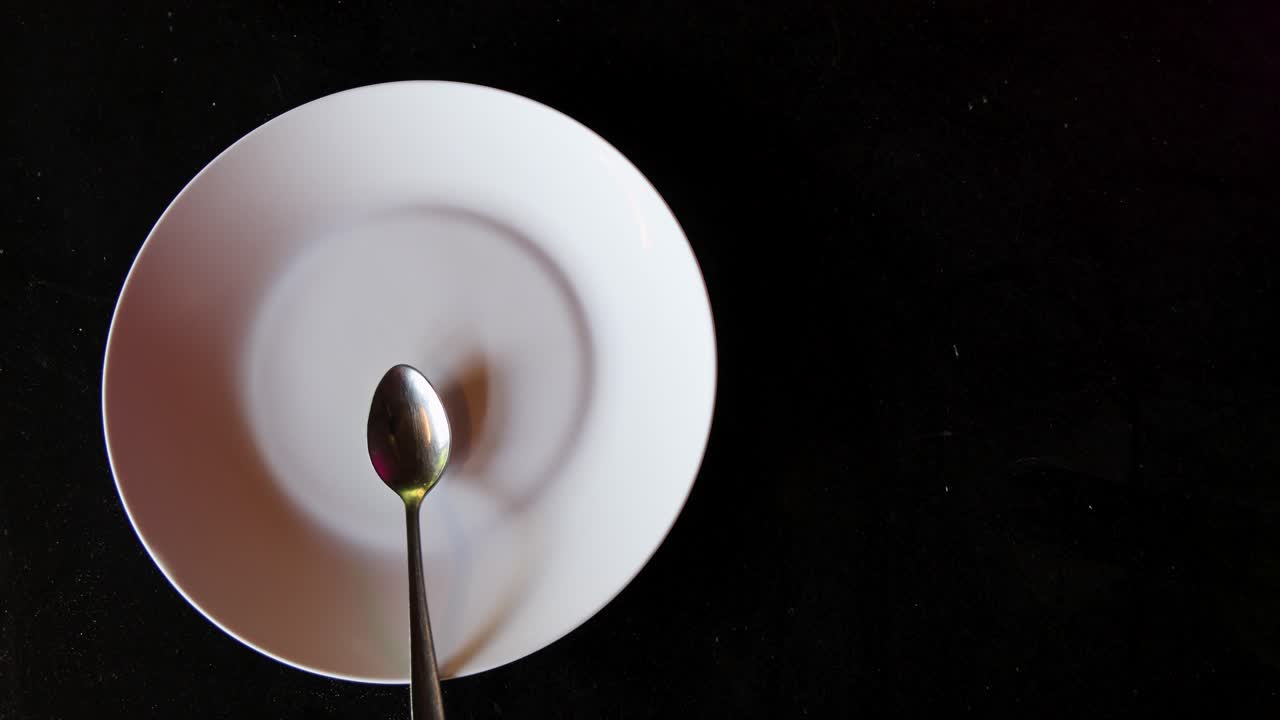 empty dish and spoon top view on black background with copy space