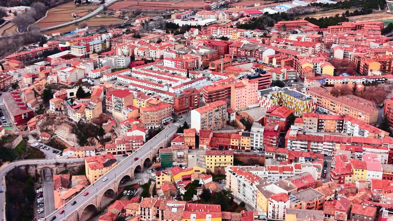 Architettura storica e ponte in pietra, Teruel, Spagna. Vista dall'alto di una strada tortuosa, diversi edifici, tetti in tegole rosse e una struttura di viadotto ad arco.