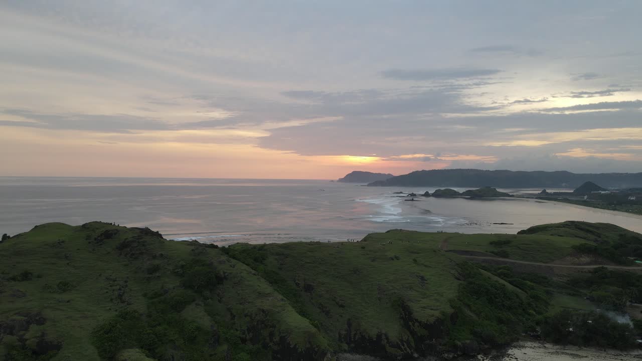 Pemandangan Udara Panorama Matahari Terbenam di Atas Samudra dan Bukit Hijau Subur.