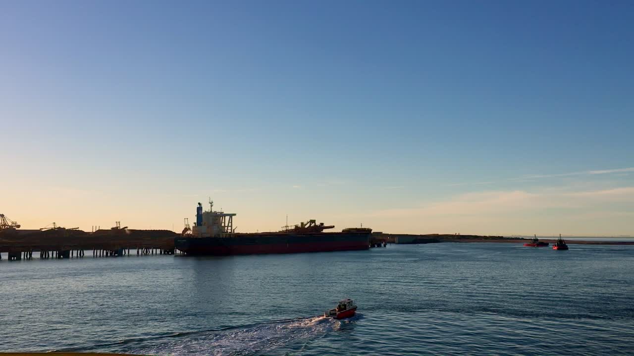 바다로 향하는 작은 예인선과 정박한 벌크 화물선의 정적 샷