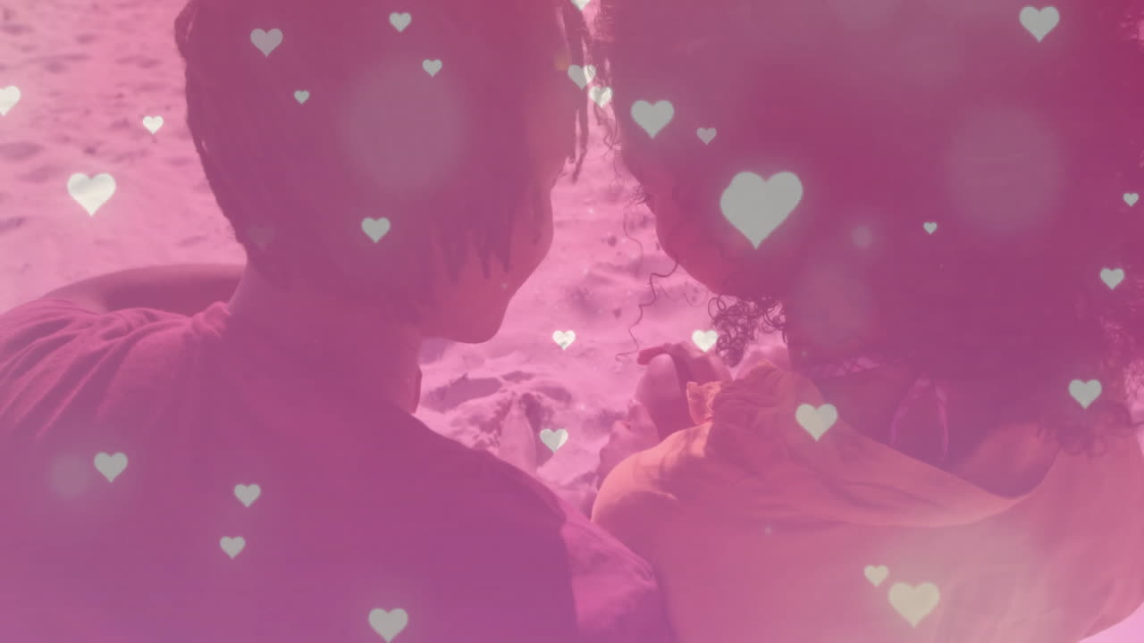 해변에서 안고 있는 두 인종의 커플에 대한 사랑이 떨어지는 애니메이션