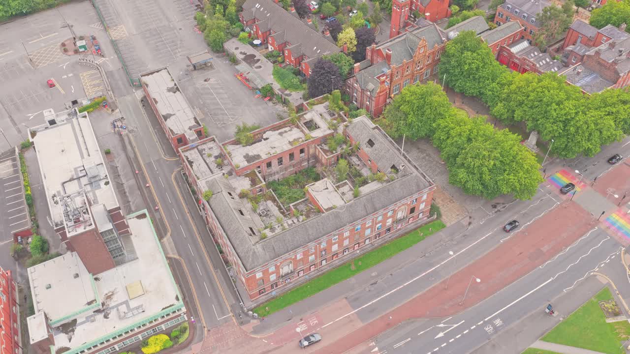Drone aerial of the abandoned Salford Crescent Police Station, with Chapel Street, Crescent road, University of Salford buildings, rainbow crossing, and nearby historic redbrick houses visible