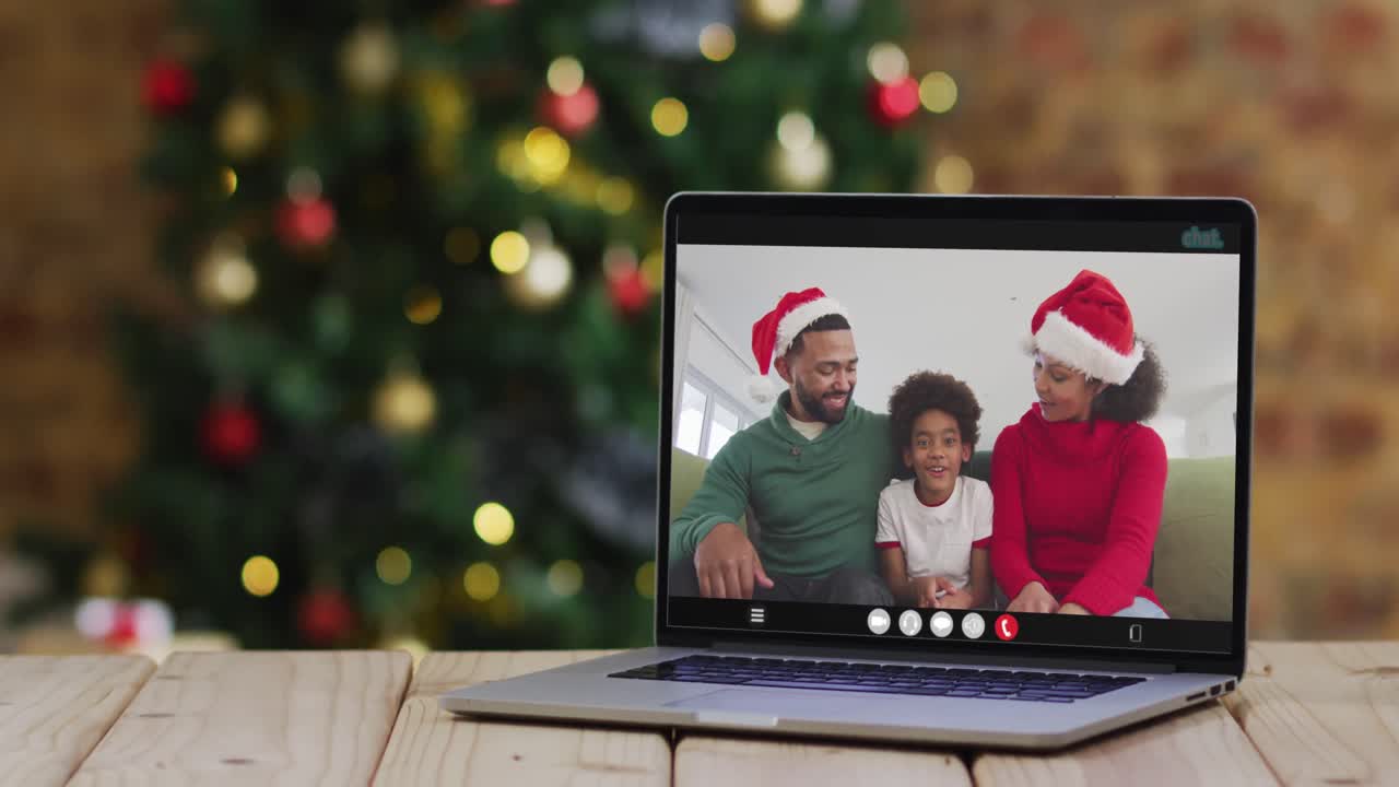 familia feliz usando sombreros de santa en una llamada de video portátil, con decoraciones de navidad y árbol