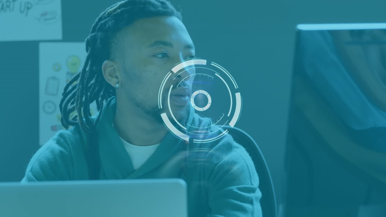 Animation of scanning icon moving over african american businessman with dreadlocks using laptop