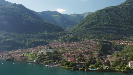 Ossuccio,-italy-with-lake-como,-lush-greenery,-and-mountains-in-bright-daylight,-aerial-view