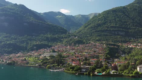 ossuccio, italia con el lago como, la vegetación exuberante y las montañas a la luz del día, vista aérea