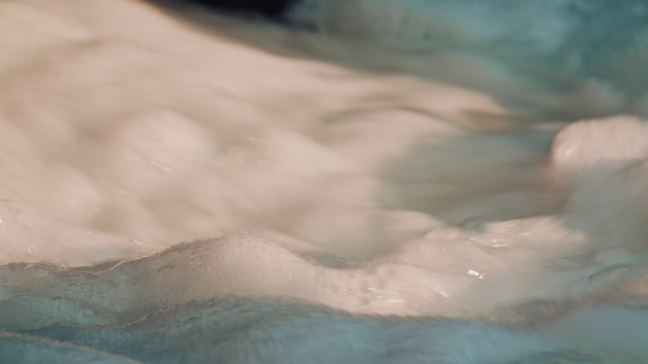 Close up of thick white foam swirling in moving water, creating a soft textured visual