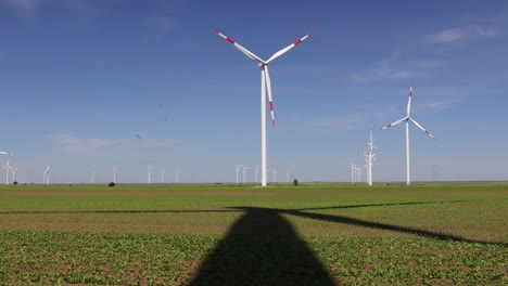 long shadow under windmill, large wind power turbines spinning to generating clean, green, renewable energy