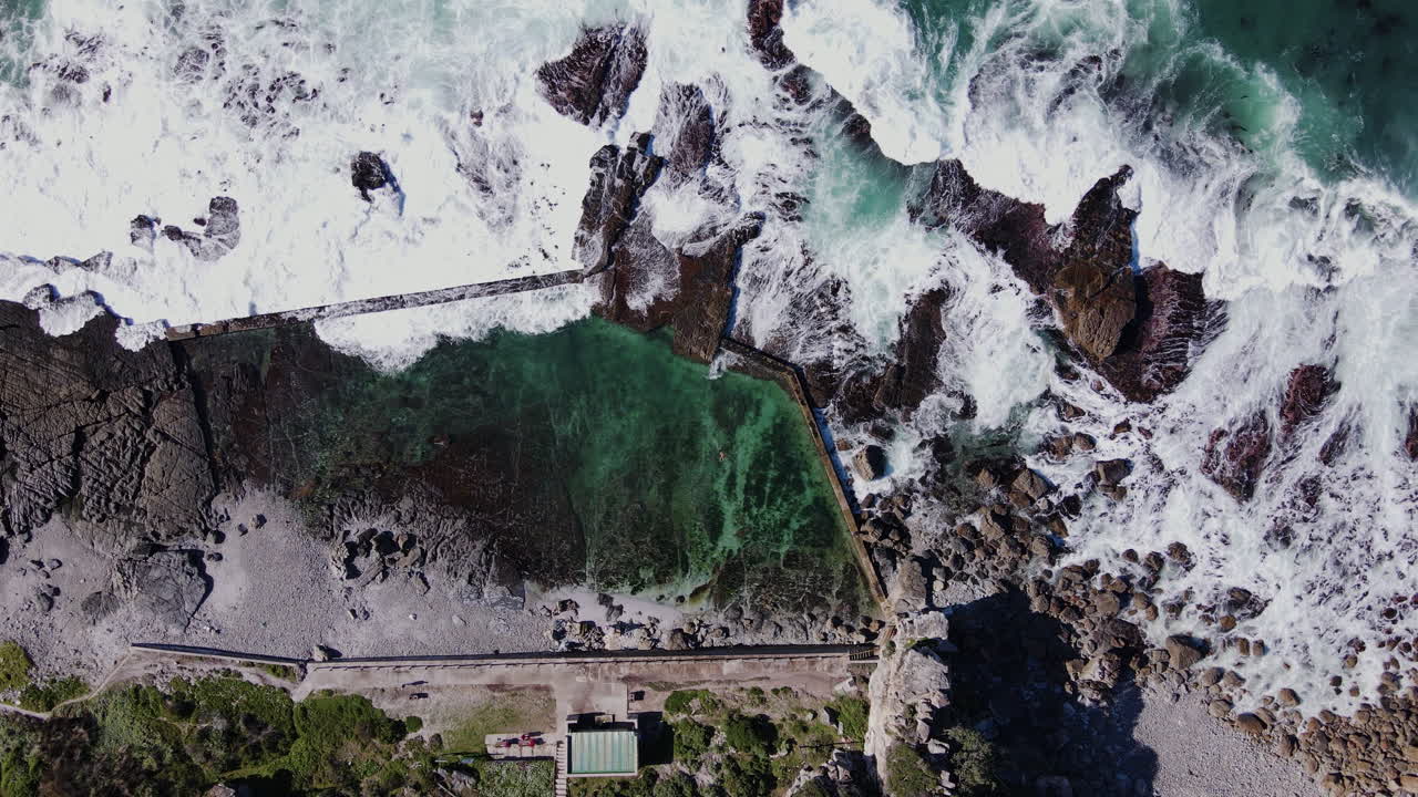 남자 수영과 바다 조수 웅덩이에 충돌하는 파도의 공중