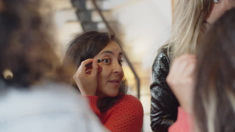 Cheerful-woman-looking-at-mirror-and-applying-eyeliner