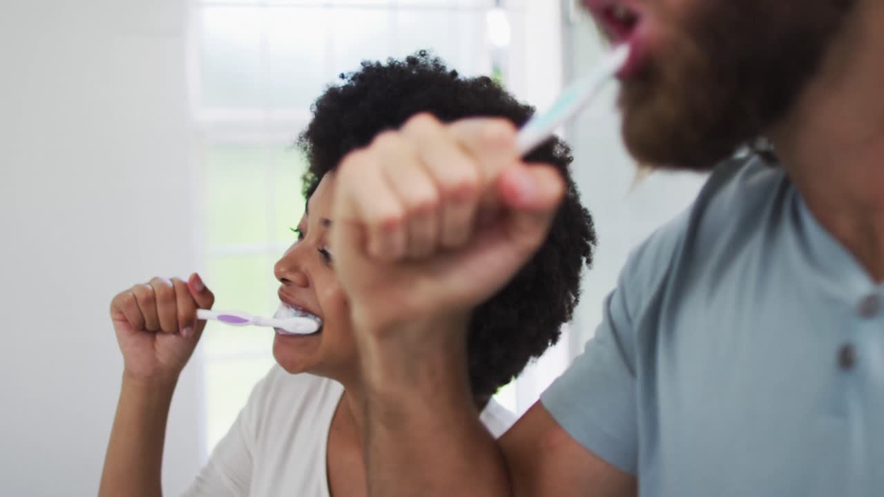 Mixed race couple brushing together in the bathroom