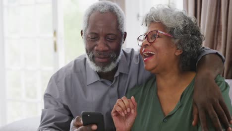 una pareja de ancianos afroamericanos riendo en casa. distanciamiento social en cuarentena