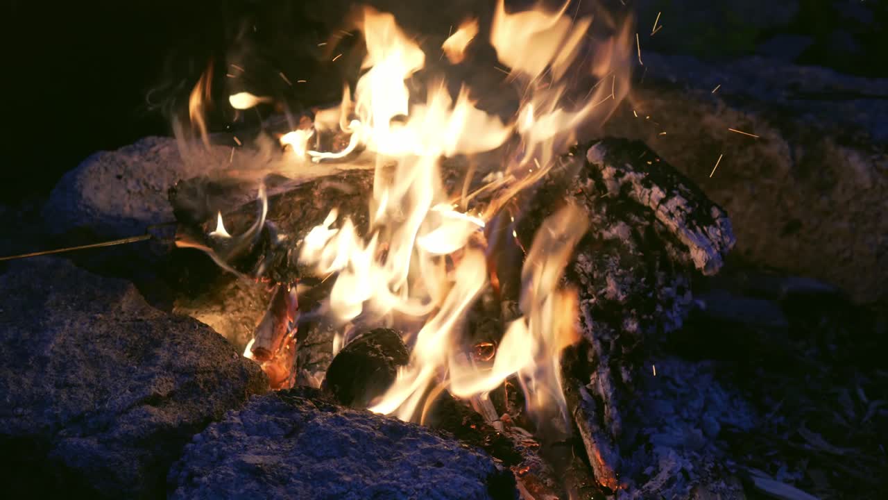 fogata siendo avivada antes de la barbacoa, fuera de la noche con luz de luna