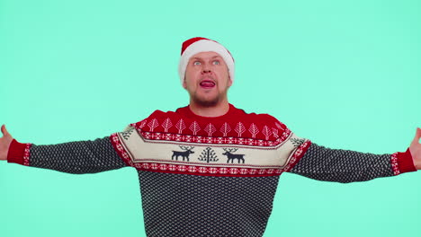 crazy man in sweater santa christmas hat demonstrating tongue out, fooling around making silly faces