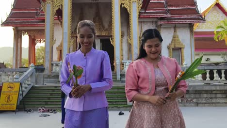 women offering flowers at a thai temple