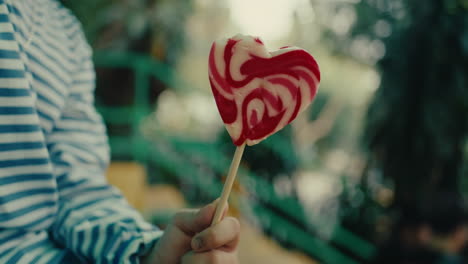 child holding a heart-shaped lollipop