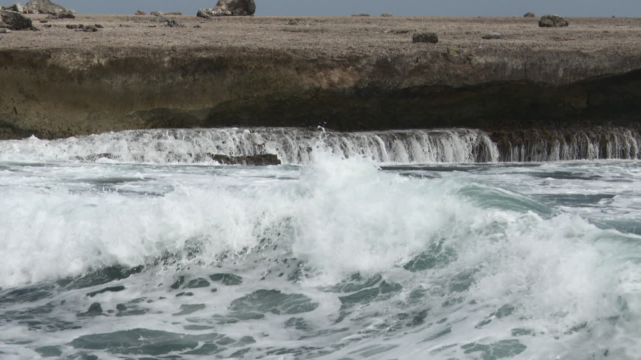 Bølger som bryter mot steiner, skaper fossefall, Bonaire