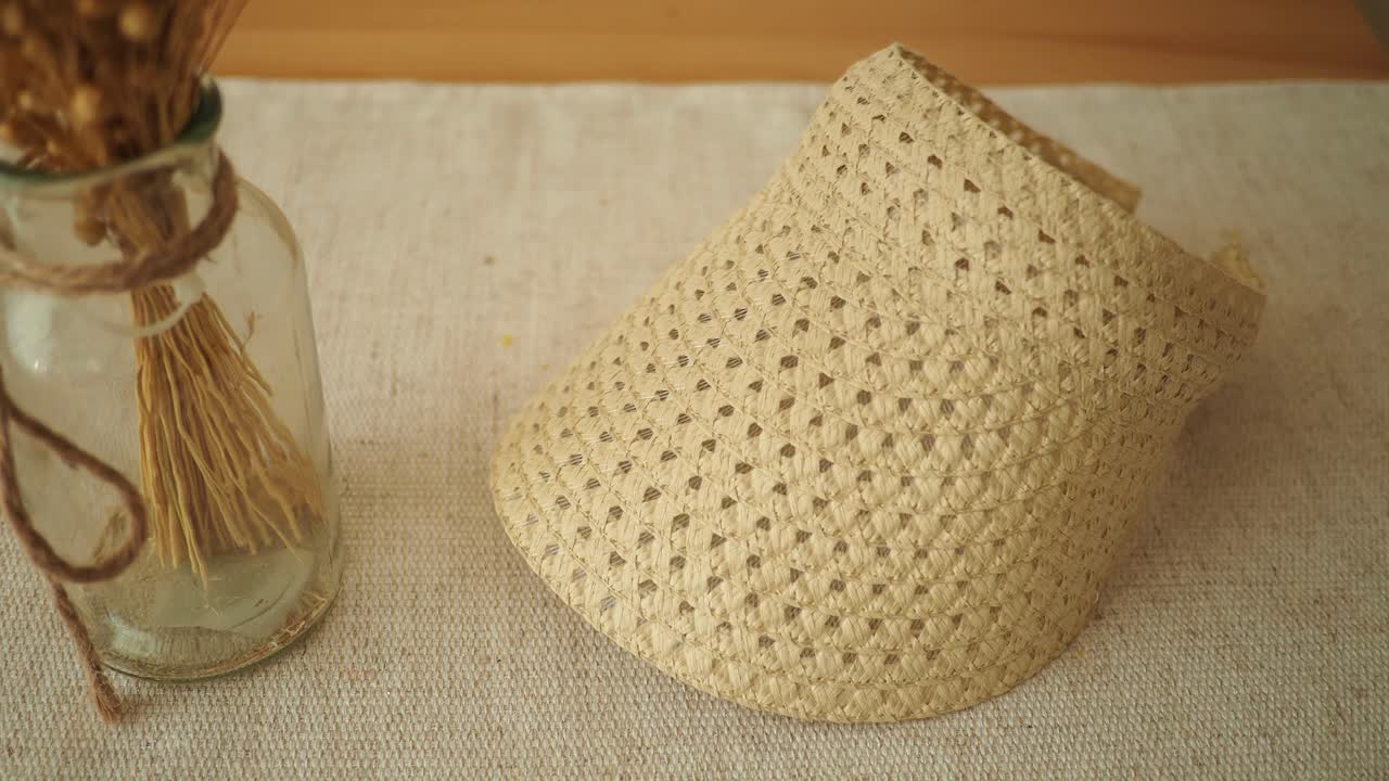 Straw Visor and Dried Grass in Glass Bottle