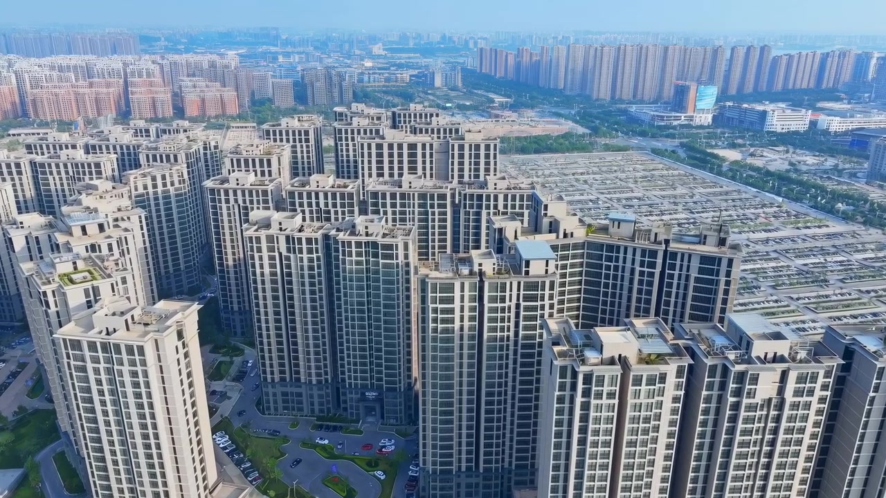 Vista aérea diurna de um complexo residencial denso, apresentando múltiplas torres de apartamentos altas de vidro e concreto. Telhados, varandas, elementos verticais repetidos.