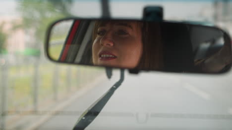 Reflection-of-woman-in-mirror-against-wipers-on-windshield