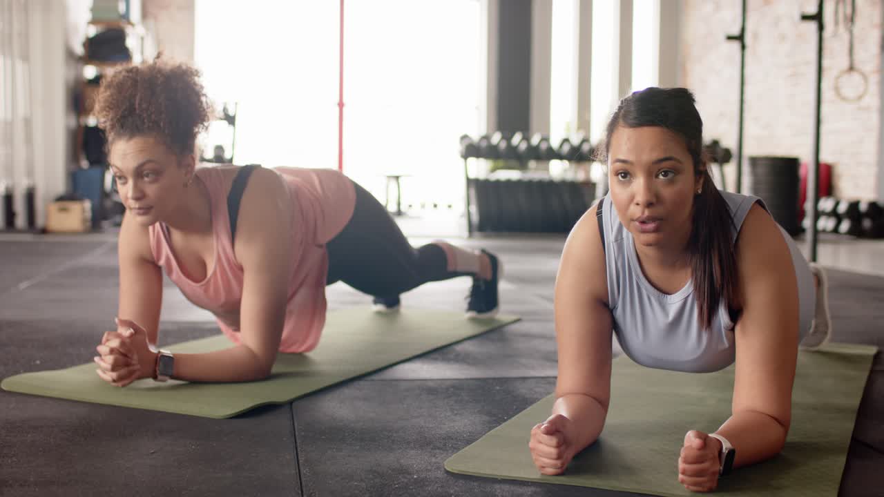 Beragam mitra wanita menempatkan matras yoga di gym, memulai forearm plank hold dengan melibatkan otot inti