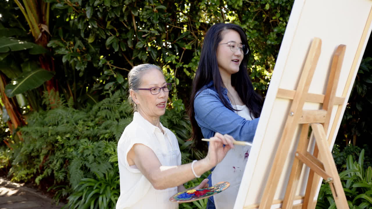 Painting on canvas, Asian grandmother and granddaughter enjoying outdoor art activity together