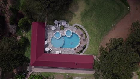 a women swimming on her back in a pool as drone ascends to reveal luxury resort