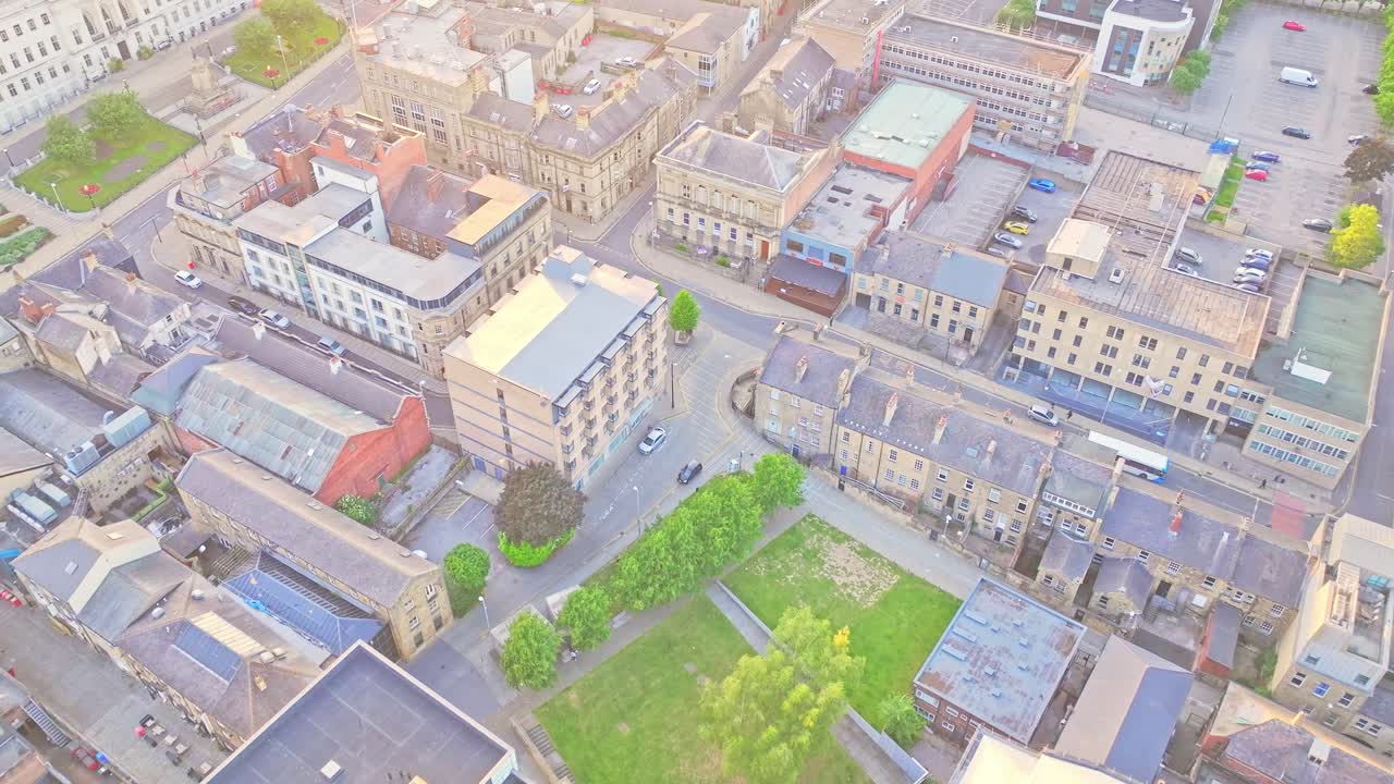 High-angle drone view over Barnsley Town Centre in South Yorkshire, England, showing historic stone buildings, streets, and a small green park illuminated by soft daylight