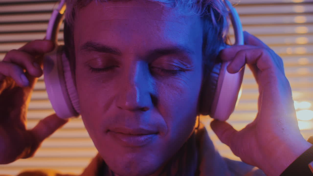 Male DJ Enjoying Music in Headphones in Neon Studio