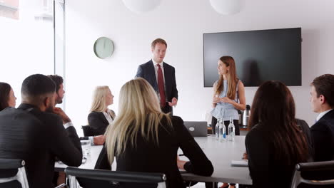 Young-Businessman-And-Businesswoman-Addressing-Group-Meeting-Around-Table-At-Graduate-Recruitment-Assessment-Day