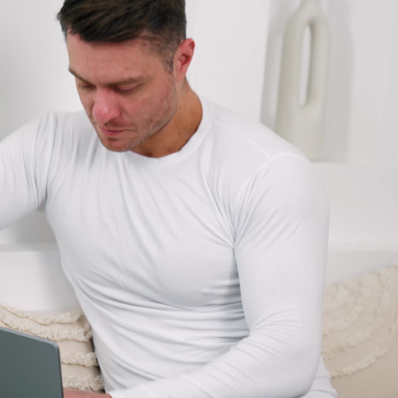 Uomo caucasico che indossa una camicia bianca apre il suo portatile. Lavorare da casa in remoto dall'ufficio.
