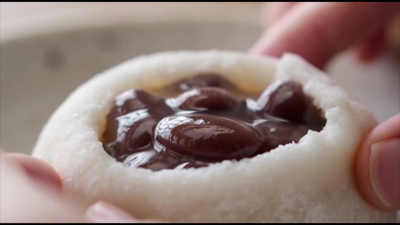 Tangan Membuka Mochi Segar Panas dengan Isian Kacang Merah