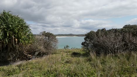 Cinematic-drone-sweeping-along-a-coastal-headland-to-reveal-a-hidden-ocean-bay-with-breaking-waves