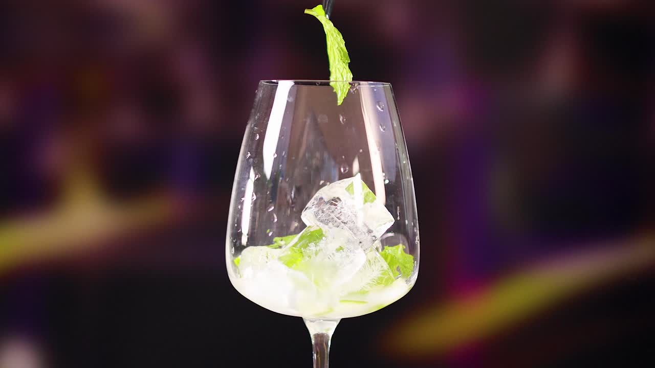 A step-by-step creation of a mojito cocktail with ice, mint, and stirring in a vibrant bar setting