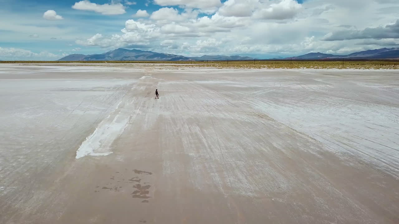 Orbit Aerial View of Female Figure in Endless White Salt Flat Under Beautiful Sky, Salta, Argentina