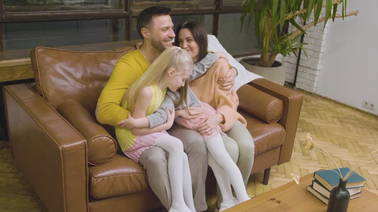 Zoom indietro su una famiglia felice che si abbraccia e trascorre del tempo insieme seduta sul divano a casa.