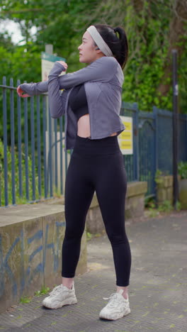 Vertical-Video-Of-Young-Woman-Tying-Laces-On-Training-Shoe-And-Stretching-Before-Exercising-Running-Along-Urban-Street-2