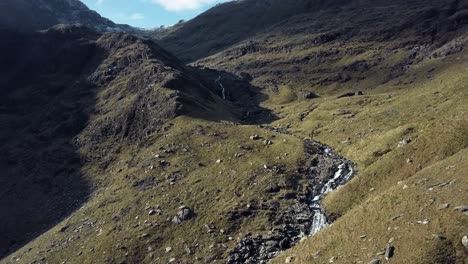 Luftbahnansicht-Des-Kleinen-Gebirgsflusses-Mit-Einigen-Schatten-über-Den-Hügeln