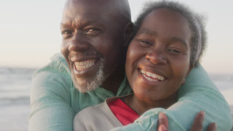 portrait of happy senior african american couple embracing at beach, in slow motion