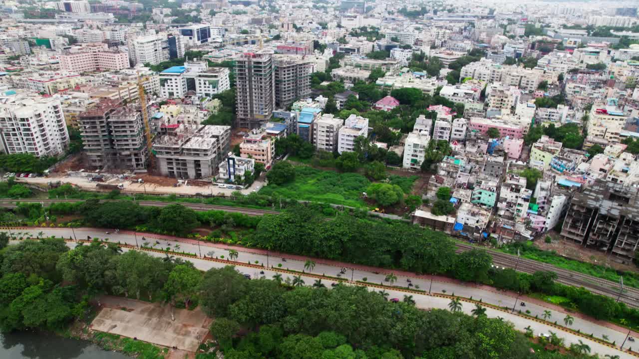 Edifici con PVNR Marg, vegetazione e binari ferroviari vicino al lago Hussain Sagar, Hyderabad. Di giorno, push-in, tilt-down, ripresa con drone, 4K
