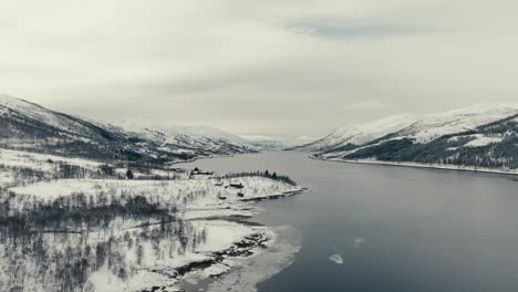 snow-covered mountains and coastal village during winter near svolvaer, norway. aerial drone shot