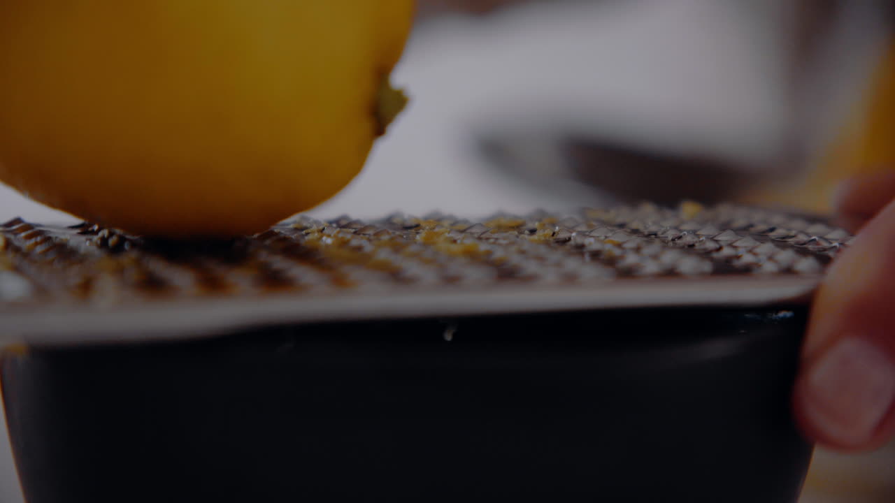 Chef Grates Lemon Zest With A Grater into a small cup detail close up