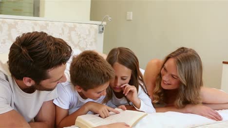 Familia-Feliz-En-La-Cama-Leyendo-Un-Libro