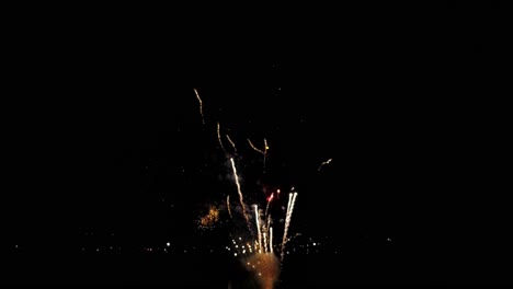 a drone view of july 4th fireworks, captured at half speed, with multiple bursts in all colors on a calm summer night